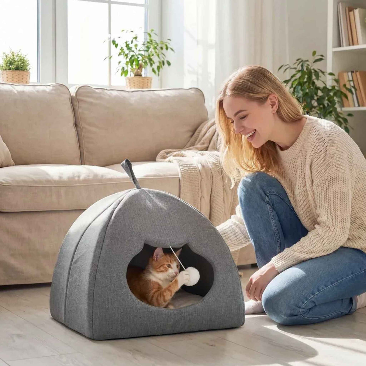 Cat playing with dangling toy in cat cave in living room