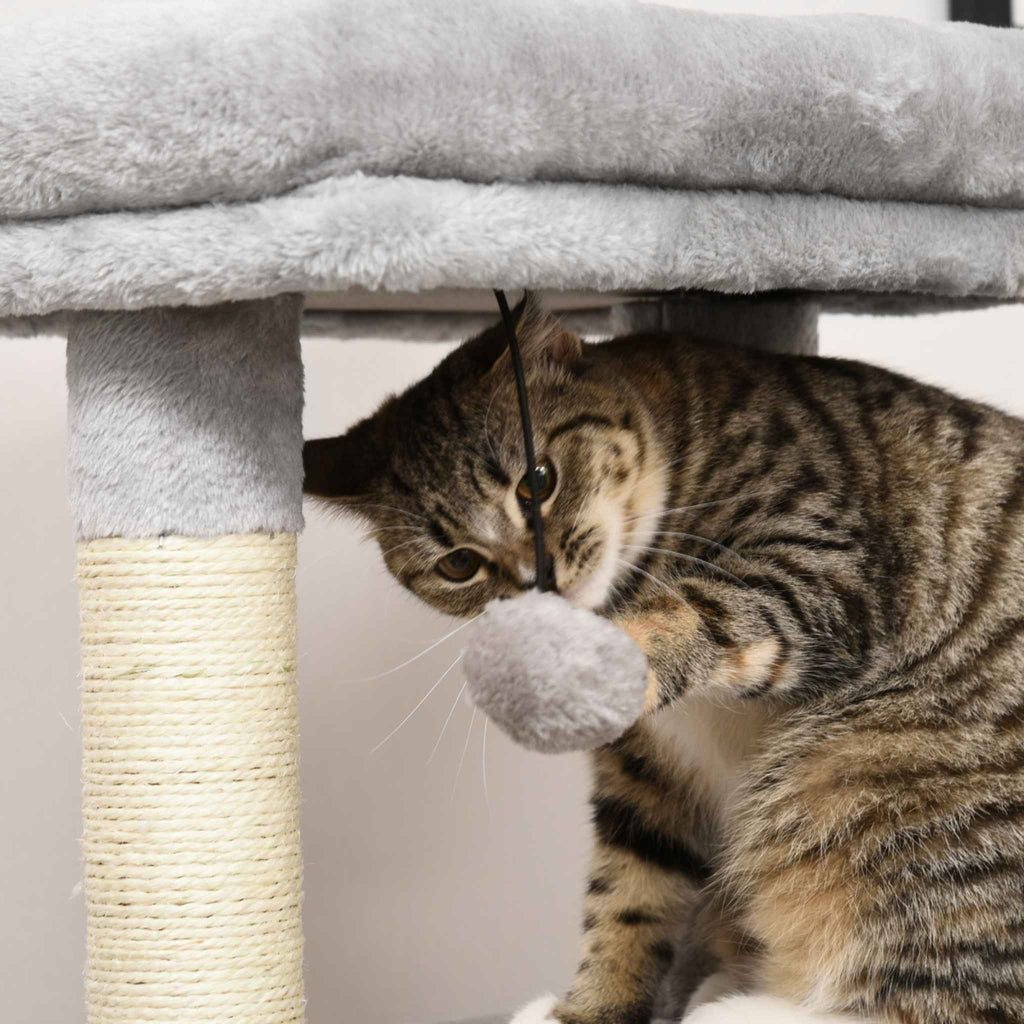 Cat playing with dangling toy on grey cat tree