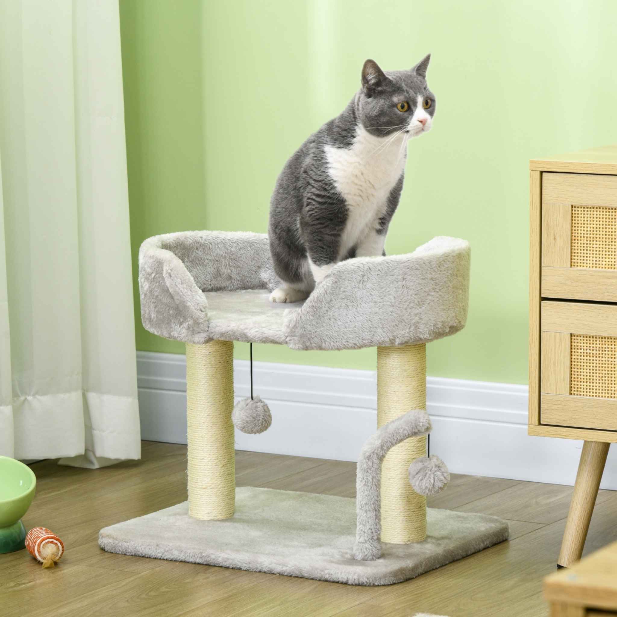Cat sitting on top perch of grey cat tree in living room