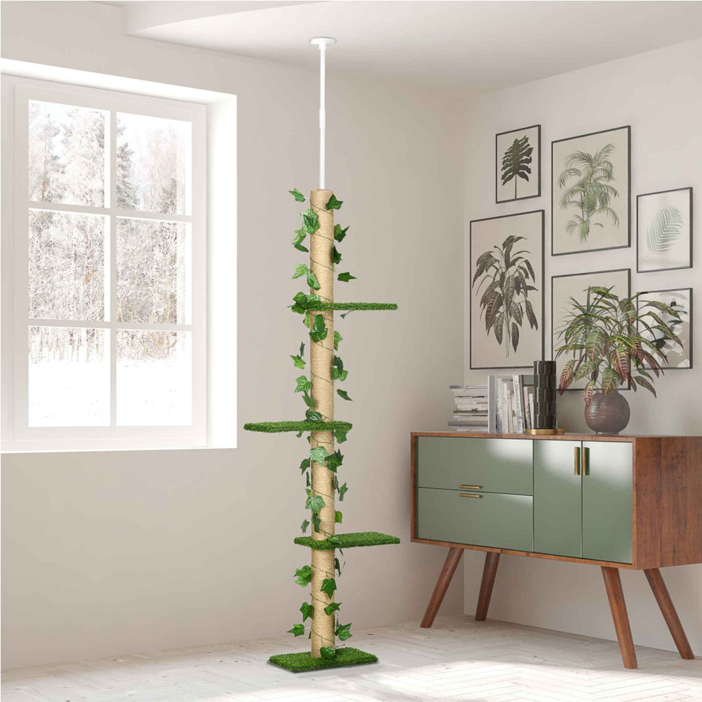 A tall cat tree with jute rope pole, green artificial grass platforms, and ivy vines, shown in a bright room next to a window and a green cabinet