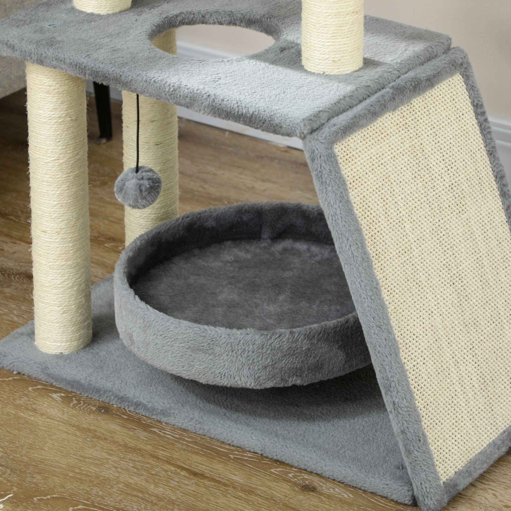 Dangling toy attached to grey cat scratching tree