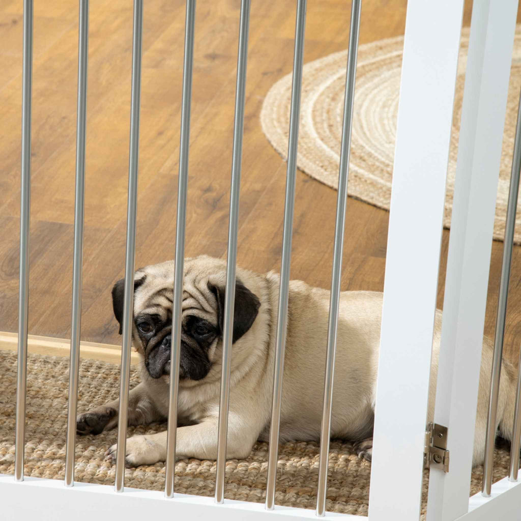 Dog laying behind white pet gate