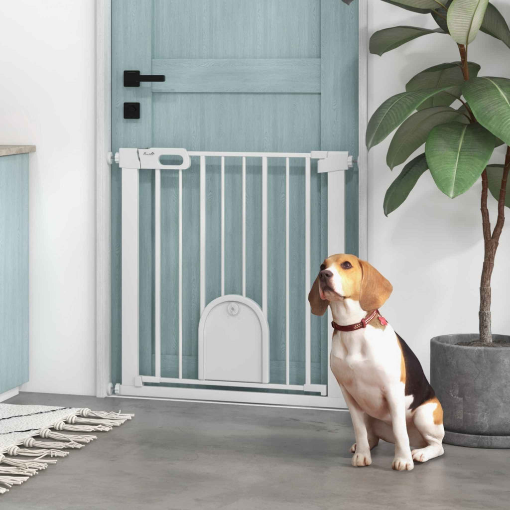Dog sitting in front of narrow white dog gate with cat door