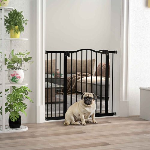 Pug sitting in front of wide black dog safety gate