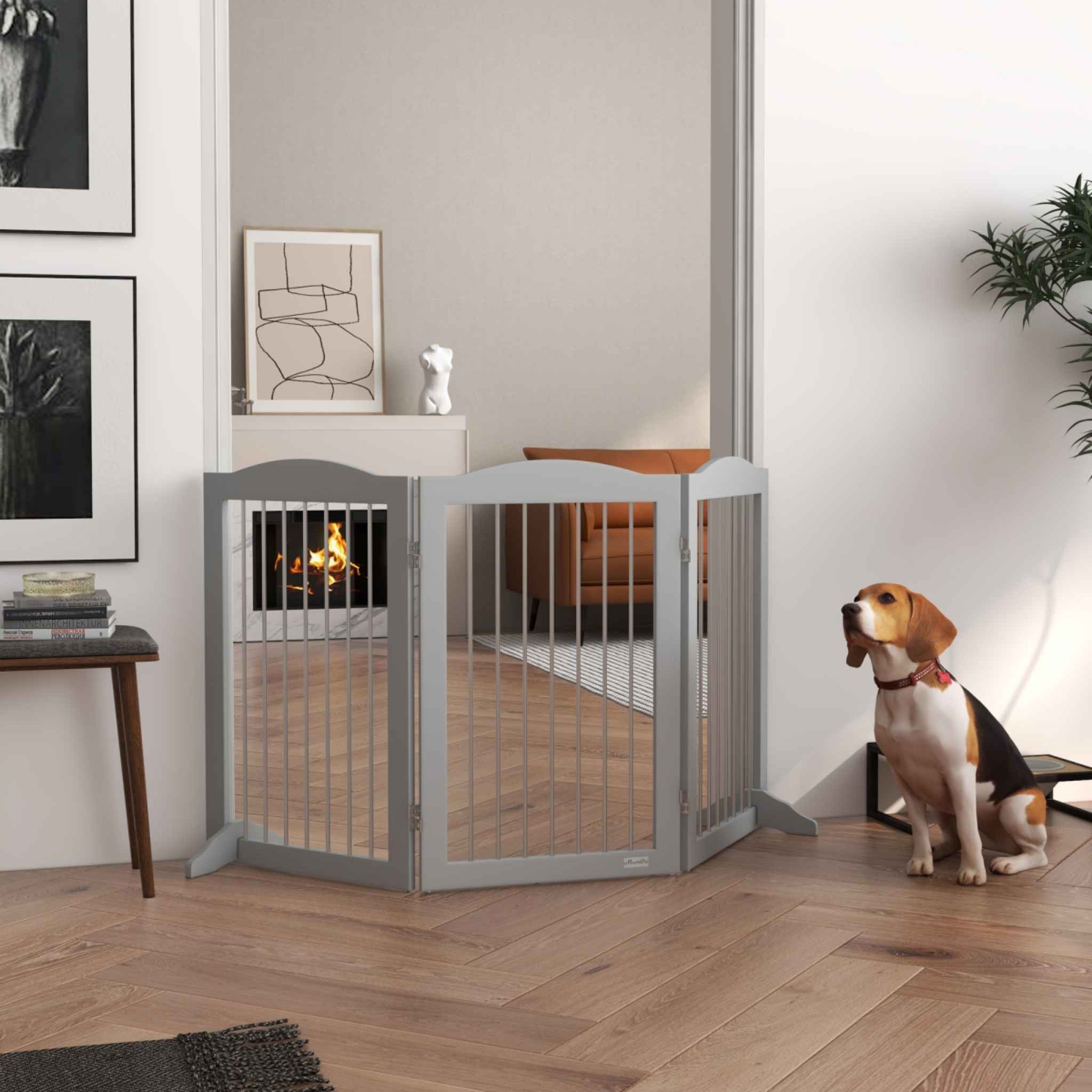 Small dog sitting in front of tall grey dog gate