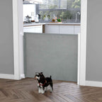 Small dog standing in front of retractable pet gate in doorway